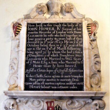Wall monument with urn above, skulls beneath, rococo scrolls. heraldry