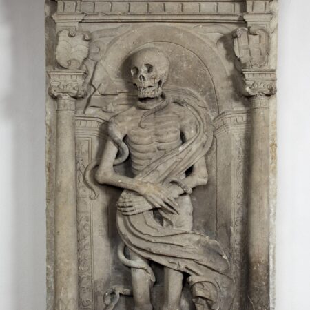 Cadaver effigy with shroud, snakes and toad, set in Renaissance style niche flanked by columns, with cherubs on the tympanum