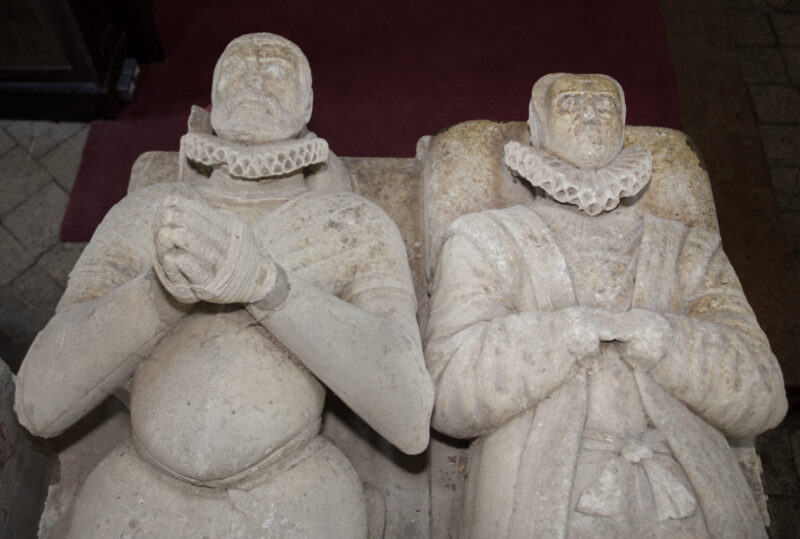 Upper part of effigies of male and female in late C16 dress. Her face has been eroded by rubbing.