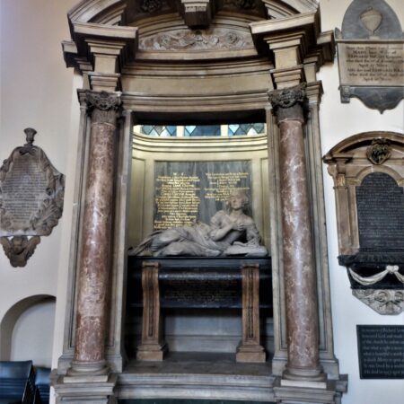 Effigy of reclining woman on tomb chest under Baroque canopy